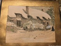 Close-up photo of the painting showing snow-covered cottage, signature, and gold border around the image.