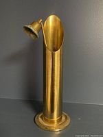 Front view of the brass candle snuffer with the holder showing the hollow cylindrical brass base and the attached snuffing cup.