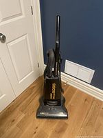 Full view of Eureka MegaBoss vacuum showing upright design, hose attachment on side, and cleaning head with brush section at bottom.