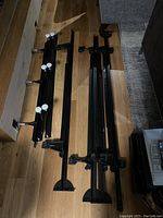 Photo showing disassembled black metal bed frame parts including side rails and support legs on wooden floor.