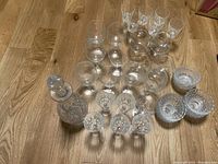 Top-down view showing the full set including decanter, brandy glasses, sherry glasses, wine glasses, decorative star glasses, and bowls arranged on wooden floor.