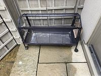 Full view of the black metal small animal enclosure cage on wheels and plastic base