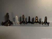 Six decorative stands arranged side by side on a flat surface against a gray background, featuring wooden and acrylic materials.