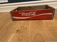 Side view of the vintage Coca Cola wooden crate with logo and metal corner reinforcements.