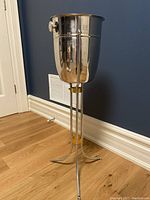 Full view of stainless steel wine bucket on tall metal stand showing cylindrical bucket and tripod base.
