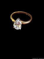 Pear-shaped cubic zirconia solitaire set in 10k yellow gold ring viewed at angle.