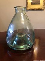 Front view of antique clear glass wasp catcher showing bulbous body and narrow neck with flared opening.