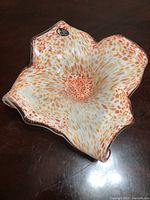 Top-down angled shot showing the flower-shaped vase with white cristal glass and orange speckled pattern, including Murano sticker.