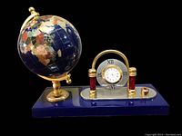 Front view of lapis lazuli gemstone globe and clock set on blue base with gold accents.