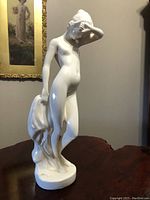 Front and side view of the vintage porcelain statue showing the woman standing with a draped cloth.