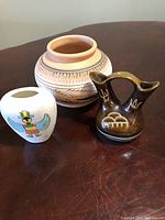 Three Navajo pottery items shown from front: large signed pot, white bird vase, brown double-spouted vessel