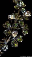 Close up of the Kenneth J Lane brooch showing green and clear rhinestones in floral and heart shapes.