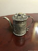Front and side view of the vintage silver filigree teapot showing the stone inlaid lid and ornate handle and spout
