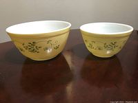 Two Pyrex bowls side by side on a wooden table showing exterior pattern and color.