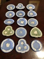 Photo showing entire collection of 15 Wedgwood Jasperware trinket dishes in blue and green, varied shapes and relief designs.