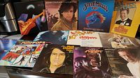 Photo showing 12 vinyl record covers laid out including Dire Straits, John Cougar, Steve Miller Band, Max Bygraves, Roger Whittaker, and others.
