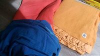 Three vintage wool blankets in blue, red, and orange folded together on floor.