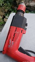 Photo showing the full body of the red and black Hilti TM8 impact drill with visible wear marks.