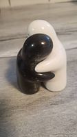 Photo of black and white hugging ghost salt and pepper shakers showing their back arms hugging each other