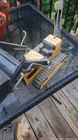 Top view of yellow Tonka backhoe toy showing arm and bucket over glass table with rust visible.