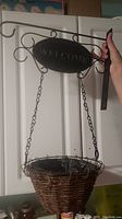 Full view of the 18 inch metal welcome sign and hanging wicker basket showing the decorative metal bracket and chains.