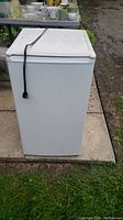 Front view of the white mini fridge with plug on top, showing compact size and clean condition.