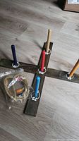 Wooden cross-shaped base with five colored pegs and plastic package of rope rings.