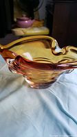 Angle view of amber glass candy dish showing wavy edge and smooth glass surface.