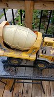Side view of vintage Tonka cement mixer toy showing yellow metal body and white plastic cement drum