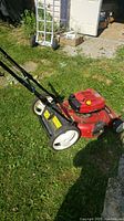 Red Toro lawnmower on grass showing the full mower deck and rear wheels with the engine cover and fuel cap visible.