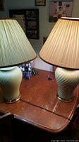 Pair of vintage ceramic table lamps with beige pleated fabric shades seen on wooden table