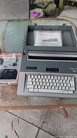 Smith Corona Typewriter full view with original carrying case and accessories on glass table.