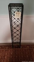 Front view of the 48 inch tall black metal wine tower with lattice pattern for holding wine bottles vertically.