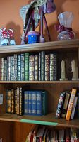 Shelf showing five Easton Press leather-bound volumes in various colors plus additional books
