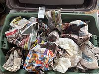 Plastic tote filled with several newspaper wrapped items, presumed to be china pieces, showing a mixed assortment of wrapped parcels