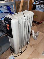 Full side view of off-white oil filled radiator heater with wheels and power cord.