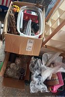 Box with various seasonal and household items including wreath, plastic crate, and some smaller boxes