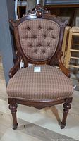Front view of Eastlake style wood chair showing red diamond pattern upholstery, button tufted backrest, and ornate wooden frame with carved crest and legs.