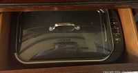 Top view of smokeless electric grill with glass lid and metal handle, showing control dial on side.