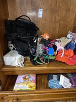 Overall view of mixed holiday accessories including tote bags, hair bands, hats, bowls, and other items arranged on wooden shelves.
