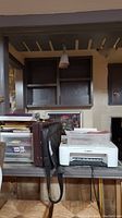 Printer, storage drawers, briefcase, laptop bag on a table under a shelf