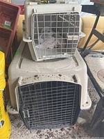 Stacked set of two plastic pet carriers, larger on bottom with black wire door, smaller on top with silver wire door and cloth inside