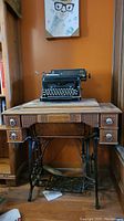 Full view of vintage sewing table with black Williams sewing machine on top, showing carved front and metal treadle base.