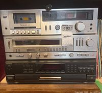 Front view of three stacked Technics stereo components, showing cassette player, AM/FM radio receiver, and CD changer.