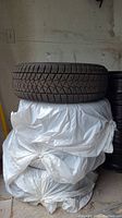 Top tire showing full tread pattern and shape, resting on wrapped stack.