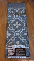 Photo of the new stair tread rug with geometric pattern and factory label showing dimensions 9x26 inches
