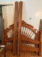 Wooden headboard and footboard leaning against the wall, showing spindle and carved details.