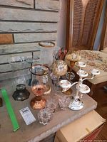 Top-down view of assorted metal and glass candle holders on table, showing candle sticks, candelabra, and bases with glass tops
