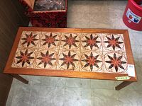 Top-down view of teak coffee table showing tile top with starburst pattern.