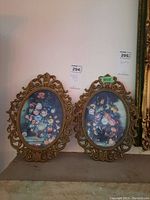 Two oval framed floral prints placed side by side showing the full view of frames and artwork.
